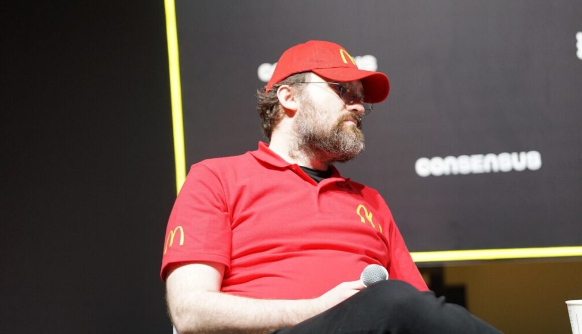 Cardano founder Charles Hoskinson speaking on stage at a crypto conference