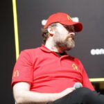 Cardano founder Charles Hoskinson speaking on stage at a crypto conference