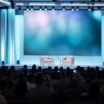 Conference stage set for a fireside chat in front of a seated audience